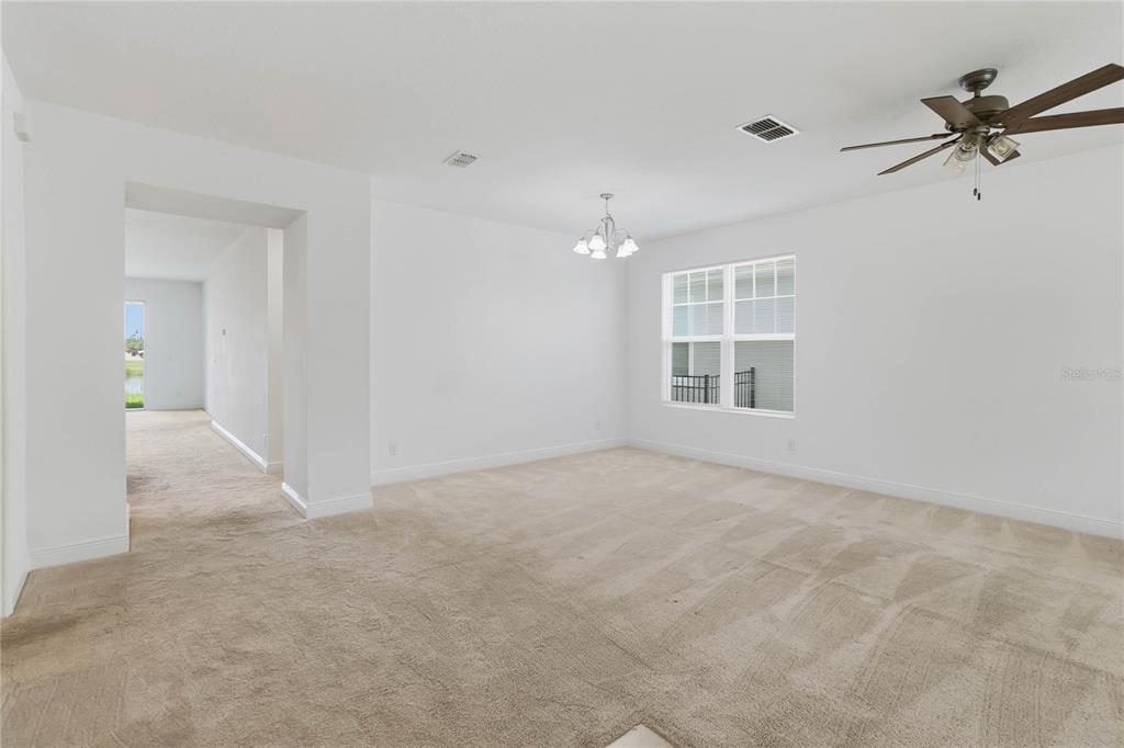 A carpeted dining area features a white chandelier, a ceiling fan, and a large window — 3393 WAUSEON DRIVE, ST CLOUD, FL