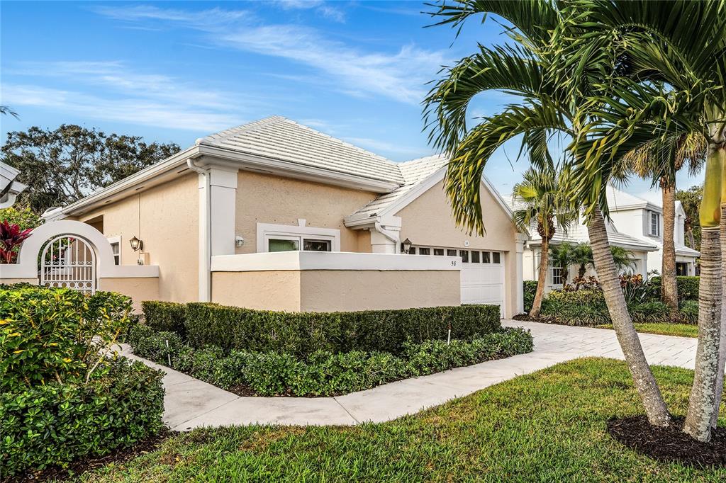 A single-story house with a beige stucco exterior, a white tile roof, and a palm tree — 58 WINDSOR LANE, PALM BEACH GARDENS, FL