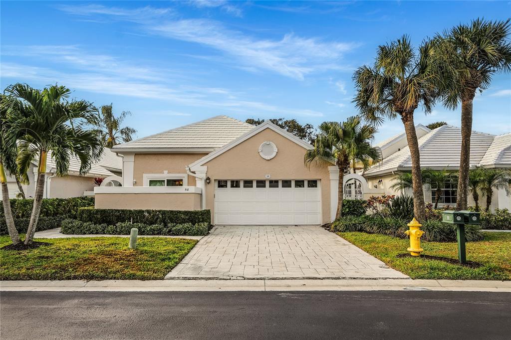 A beige single-story house with a white garage door, tile roof, and palm trees — 58 WINDSOR LANE, PALM BEACH GARDENS, FL
