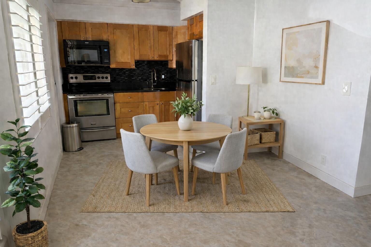 A kitchen with wooden cabinets and stainless steel appliances opens to a small dining area — 2131 NE 42nd Court # 202e, Lighthouse Point FL 33064, LIGHTHOUSE POINT, FL