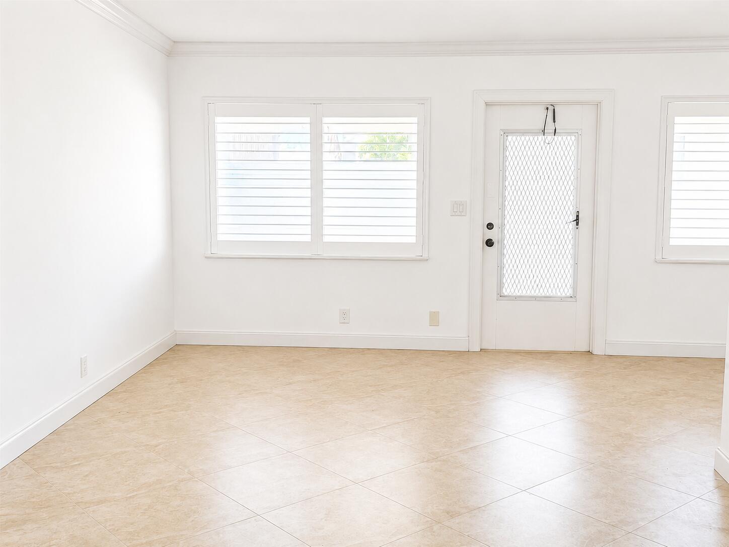 An empty room with white walls, tile flooring, plantation shutters, and a white exterior door — 2131 NE 42nd Court # 202e, Lighthouse Point FL 33064, LIGHTHOUSE POINT, FL