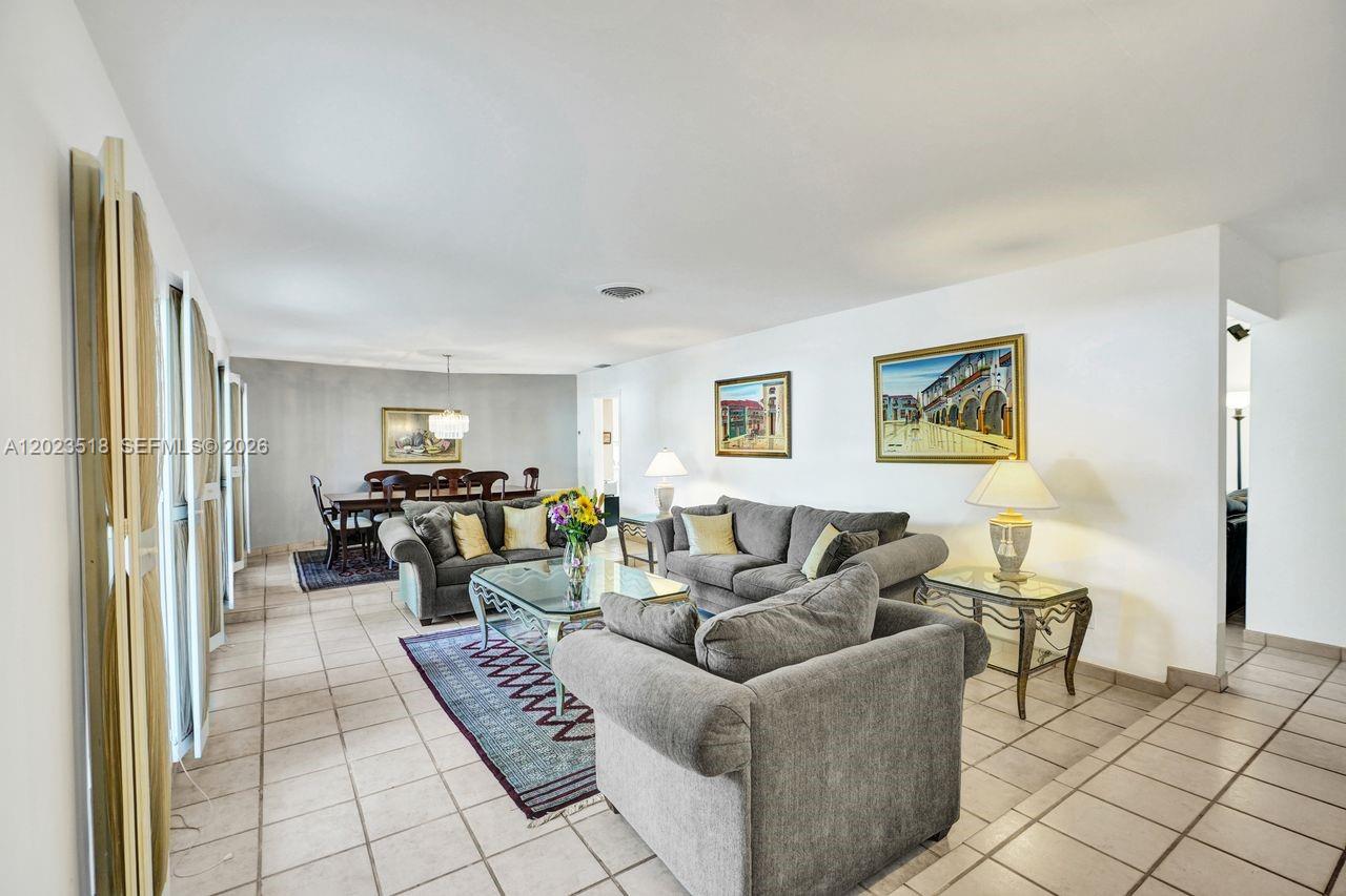A living room and dining area feature gray sofas, tile flooring, and framed wall art — 8521 SW 86th Ct, Miami FL 33143, MIAMI, FL