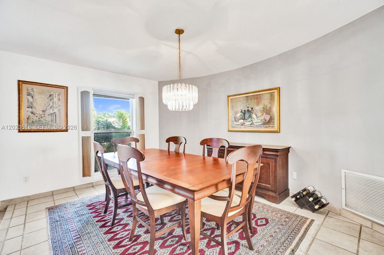 A dining room features a wooden table, six chairs, a chandelier, and a patterned rug — 8521 SW 86th Ct, Miami FL 33143, MIAMI, FL