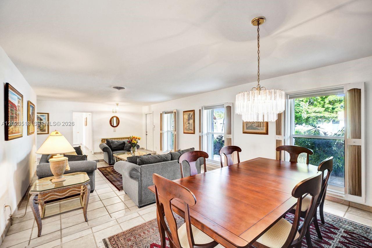 A dining area with a crystal chandelier opens into a living room with tiled floors — 8521 SW 86th Ct, Miami FL 33143, MIAMI, FL