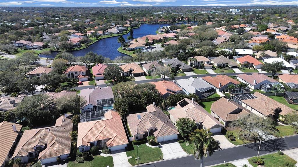 An aerial view shows a suburban neighborhood with houses surrounding a central lake — 4833 WINDMILL PALM TERRACE NE, ST PETERSBURG, FL