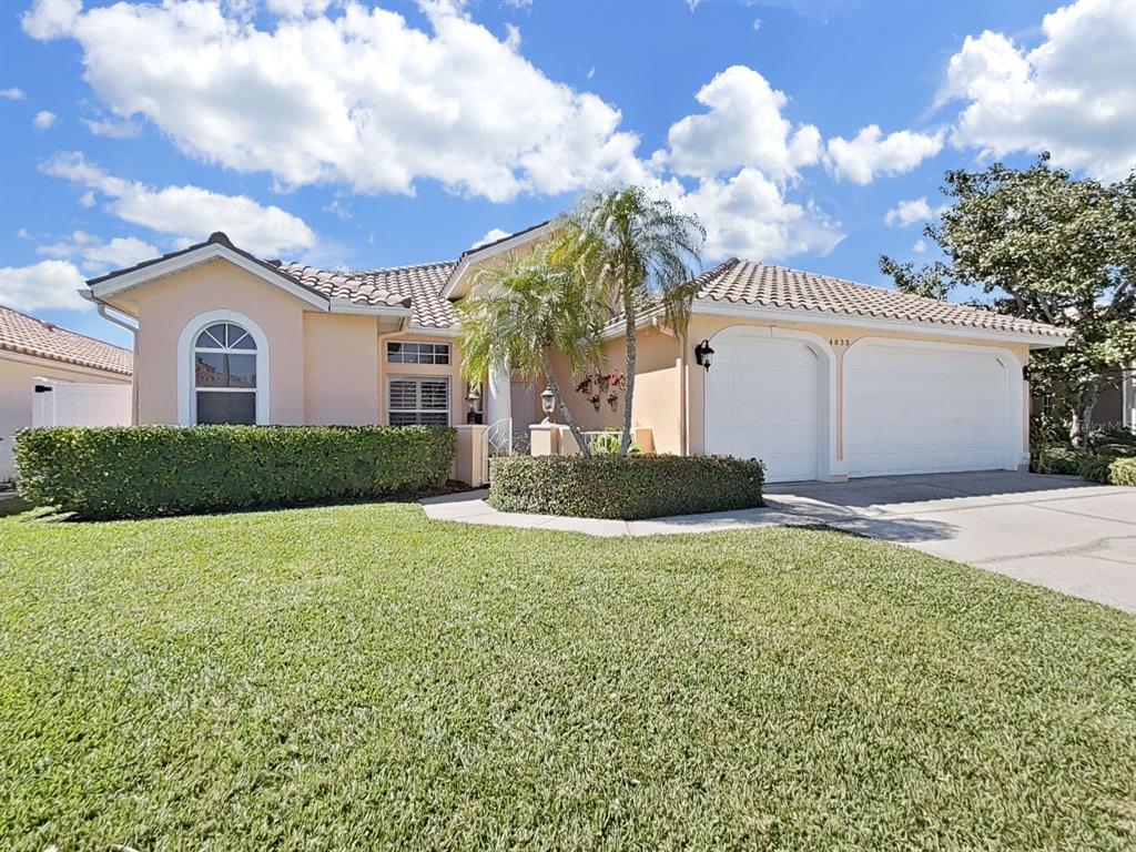 A single-story house with a beige stucco exterior, a tile roof, and a two-car garage — 4833 WINDMILL PALM TERRACE NE, ST PETERSBURG, FL