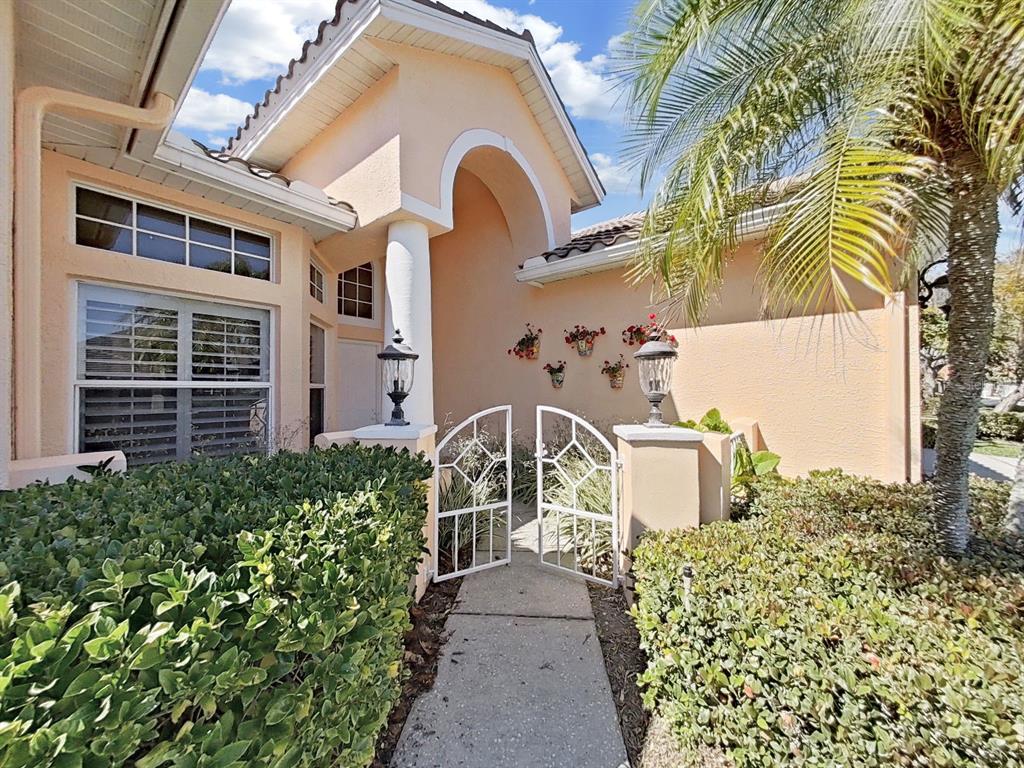 A walkway leads through a white metal gate to the front entrance of a house — 4833 WINDMILL PALM TERRACE NE, ST PETERSBURG, FL