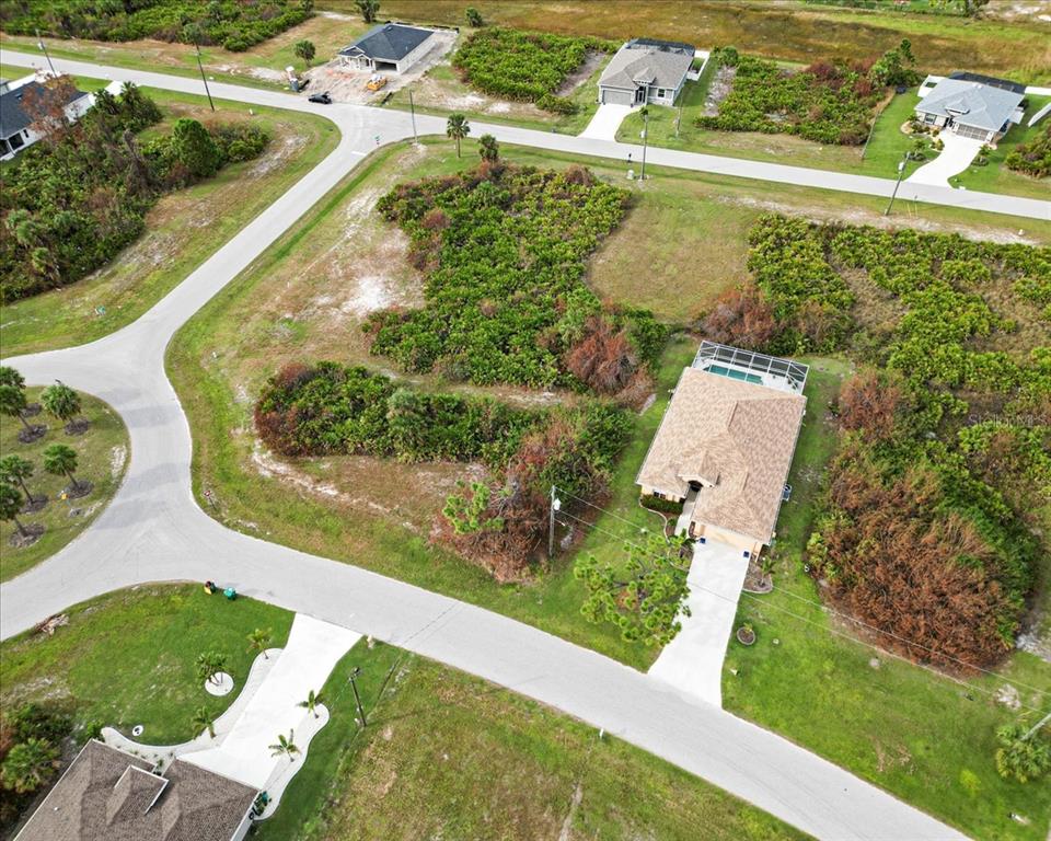 An aerial view shows a suburban neighborhood with several houses and undeveloped lots — 442 ALBATROSS ROAD, ROTONDA WEST, FL