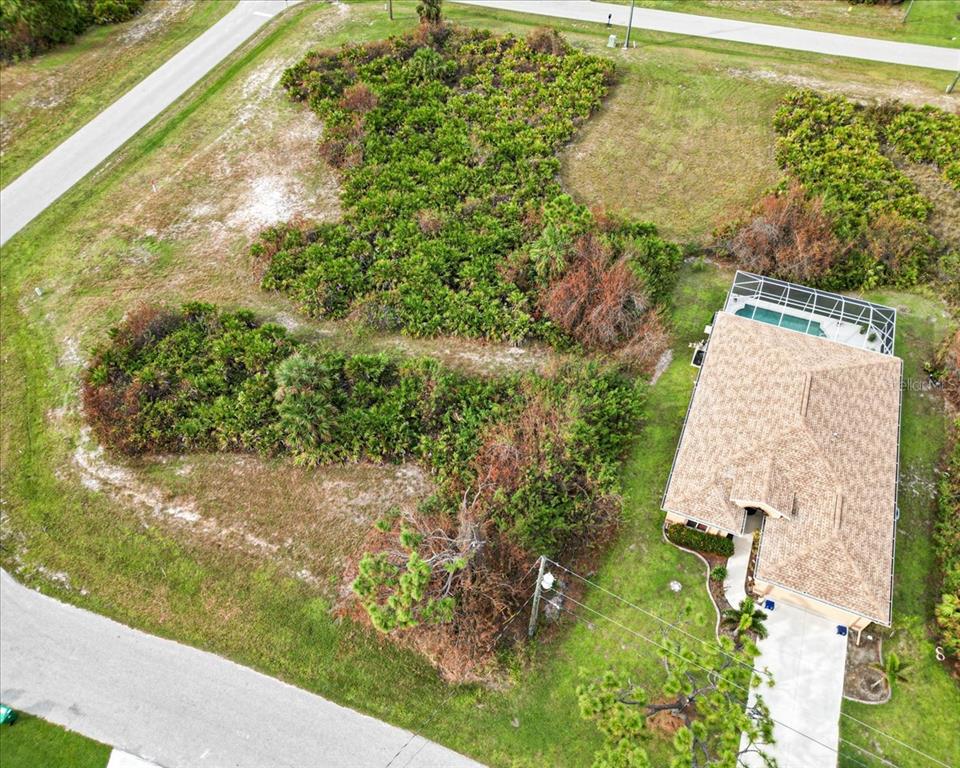 An aerial view shows a house with a pool cage next to a vacant lot — 442 ALBATROSS ROAD, ROTONDA WEST, FL
