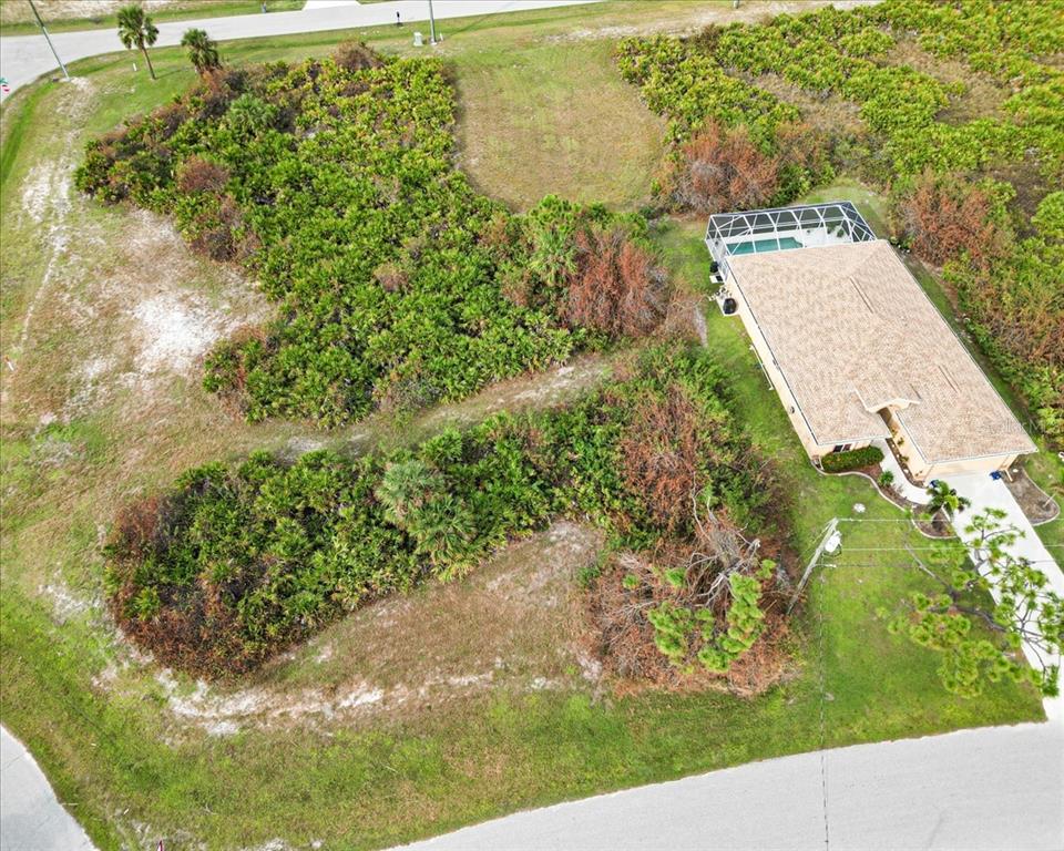 An aerial view shows a house with a pool cage next to a large, wooded lot — 442 ALBATROSS ROAD, ROTONDA WEST, FL