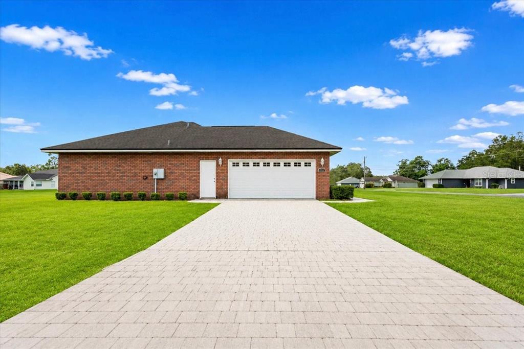 A brick house with a two-car garage and a paved driveway sits on a grassy lot — 122 SW ARROW GLEN, LAKE CITY, FL