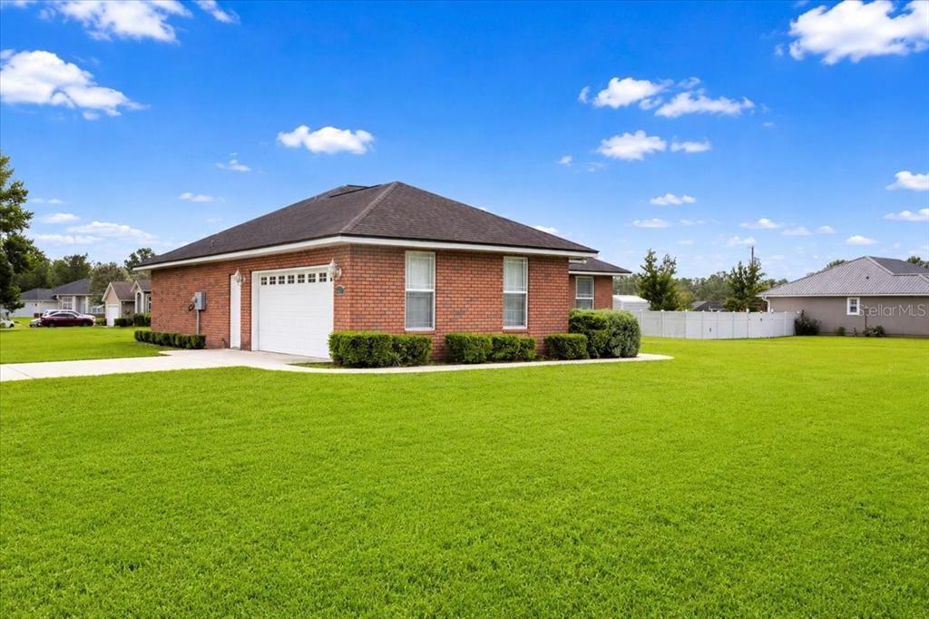 A brick house with a white garage door sits on a large, grassy lawn — 122 SW ARROW GLEN, LAKE CITY, FL