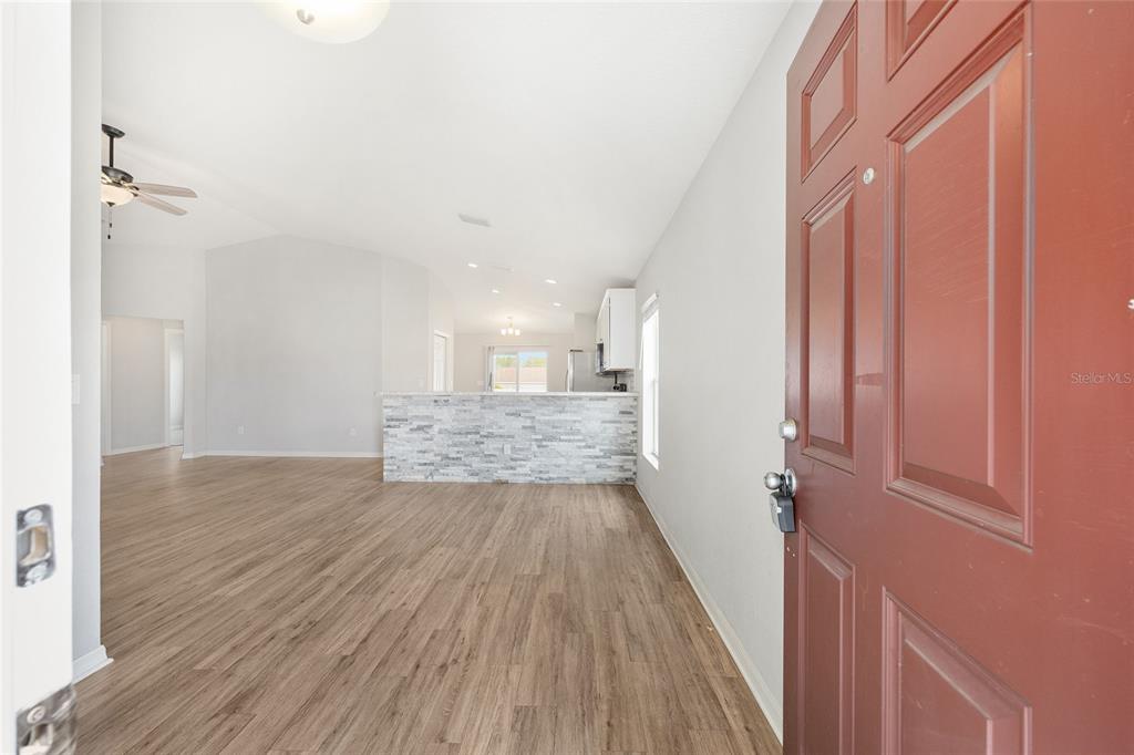 An entryway opens into a living room with wood-look flooring and a stone-faced kitchen island — 9074 SE 47TH COURT ROAD, OCALA, FL