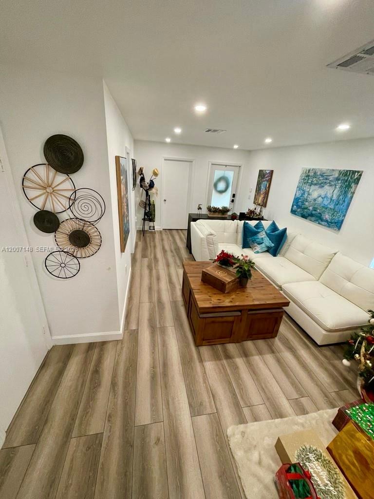 A living room features a white sectional sofa, a wooden coffee table, and wall decor — 1149 NW 126th Pl # 0, Miami FL 33182, MIAMI, FL