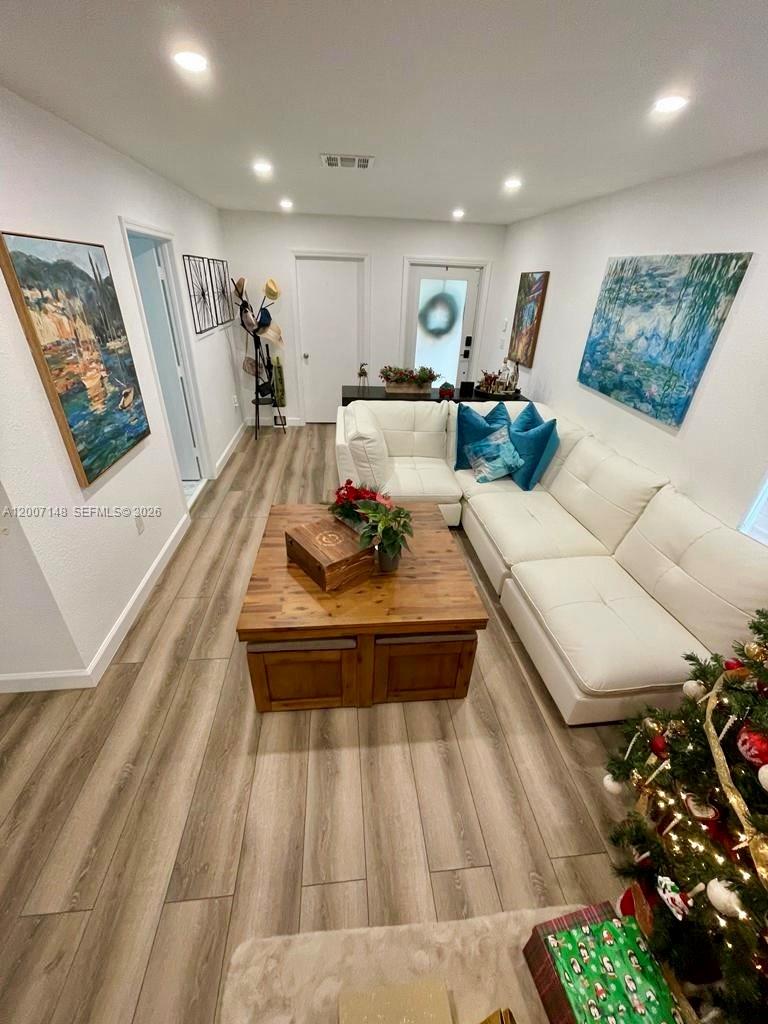 A living room features a white sectional sofa, a wooden coffee table, and wood-look flooring — 1149 NW 126th Pl # 0, Miami FL 33182, MIAMI, FL