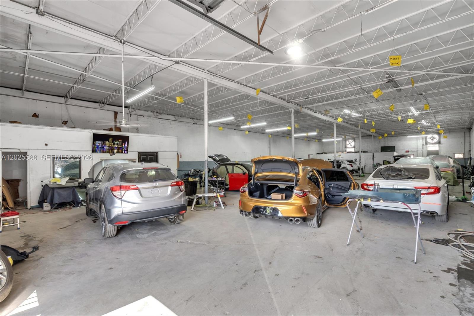 An auto repair shop interior features three cars parked on a concrete floor — 3500 NW 54th St # 5214, Miami FL 33142, MIAMI, FL