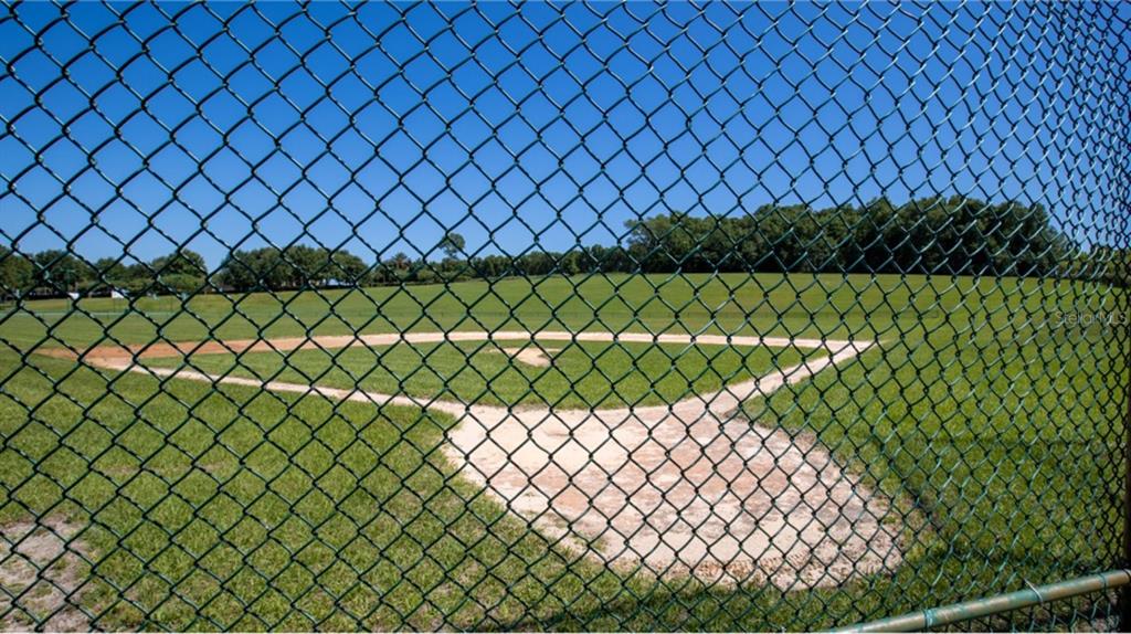A view of a baseball field with a dirt infield seen through a chain-link fence — 5579 MORANT BAY PATH, KISSIMMEE, FL