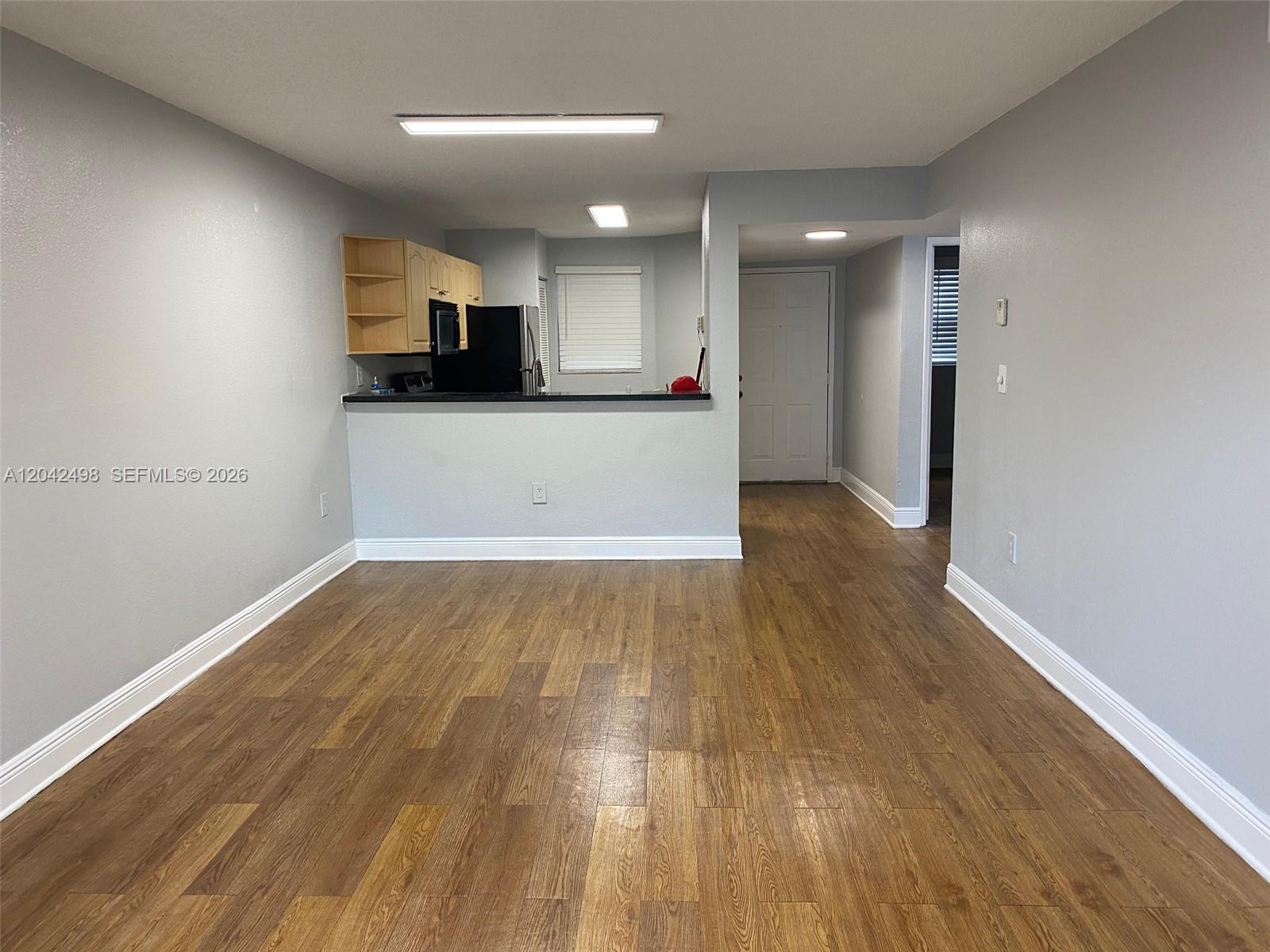 A living area with wood-look flooring leads to an open kitchen with a breakfast bar — 9981 Nob Hill Ct # 9981, Sunrise FL 33351, SUNRISE, FL