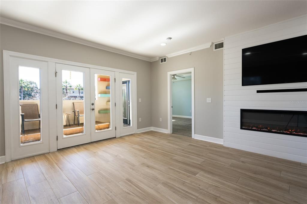 A living room features wood-look tile floors, a white shiplap fireplace wall, and glass doors — 300 BELLA HARBOR COURT UNIT 101, PALM COAST, FL