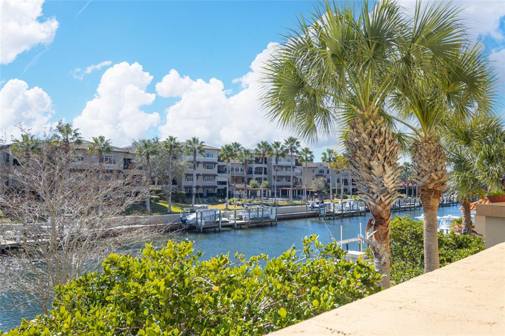 A view of a canal with boat docks and palm trees in front of apartment buildings — 300 BELLA HARBOR COURT UNIT 101, PALM COAST, FL