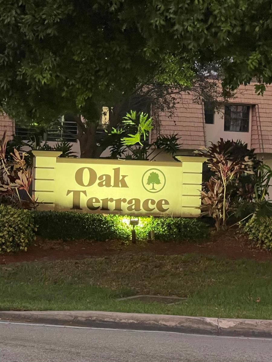 An illuminated sign for Oak Terrace stands in front of a building with landscaping — 4259 Oak Terrace Drive, FL 33463, FL