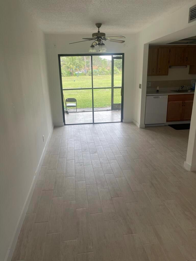 A dining area with light wood-look tile flooring leads to a sliding glass door — 4259 Oak Terrace Drive, FL 33463, FL