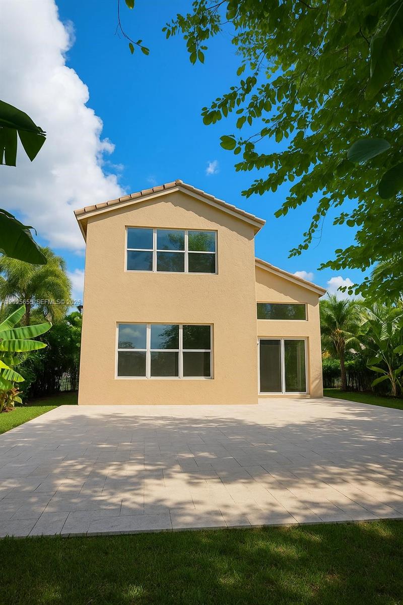 The exterior rear view of a two-story beige house features a paved patio and landscaping — 2950 SW 163rd Ave # 0, Miramar FL 33027, MIRAMAR, FL