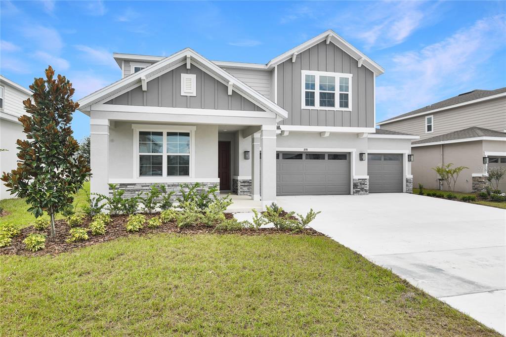 A two-story suburban house with a gray exterior, stone accents, and a three-car garage — 1698 CROOKED CREEK STREET, ST CLOUD, FL