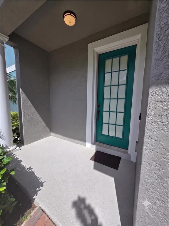 A teal front door with glass panes sits on a covered concrete porch — 10158 RIDGEBLOOM AVENUE, ORLANDO, FL