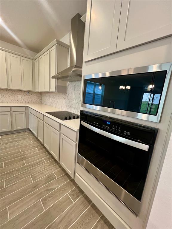 A kitchen features light gray cabinets, stainless steel appliances, and wood-look tile flooring — 2241 JUNIPER BERRY DRIVE, MINNEOLA, FL