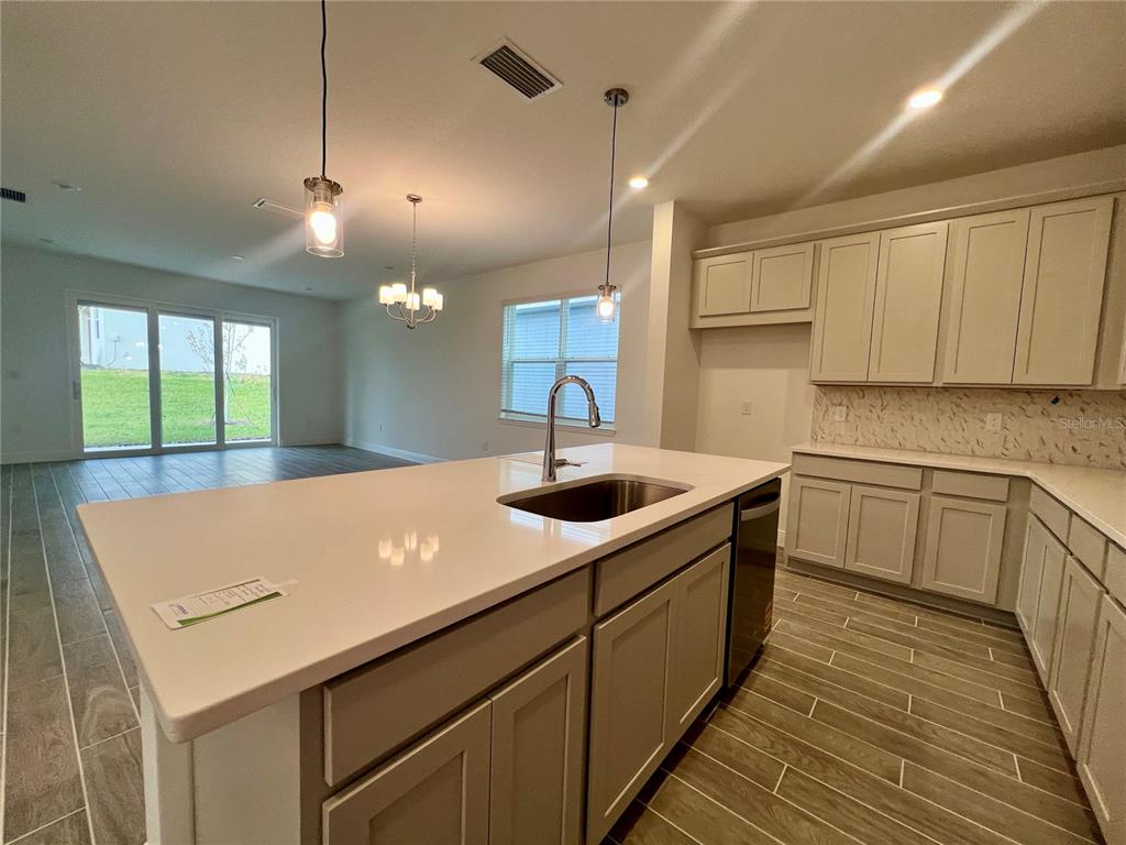 A kitchen with a large white island, light-colored cabinets, and tile flooring — 2241 JUNIPER BERRY DRIVE, MINNEOLA, FL