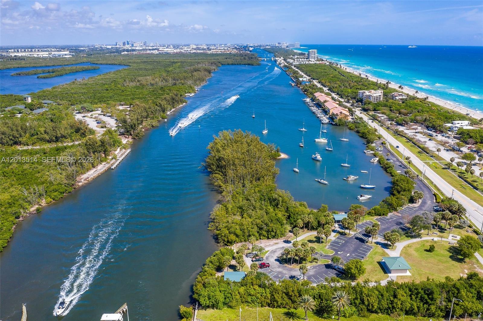 An aerial view shows a waterway with boats, a park, and a nearby beach — HOLLYWOOD, FL