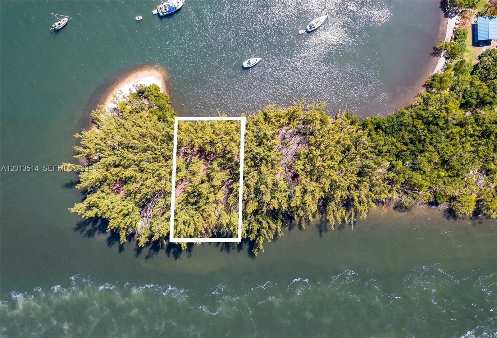 An aerial view shows a rectangular plot of land outlined in white on a wooded island — HOLLYWOOD, FL
