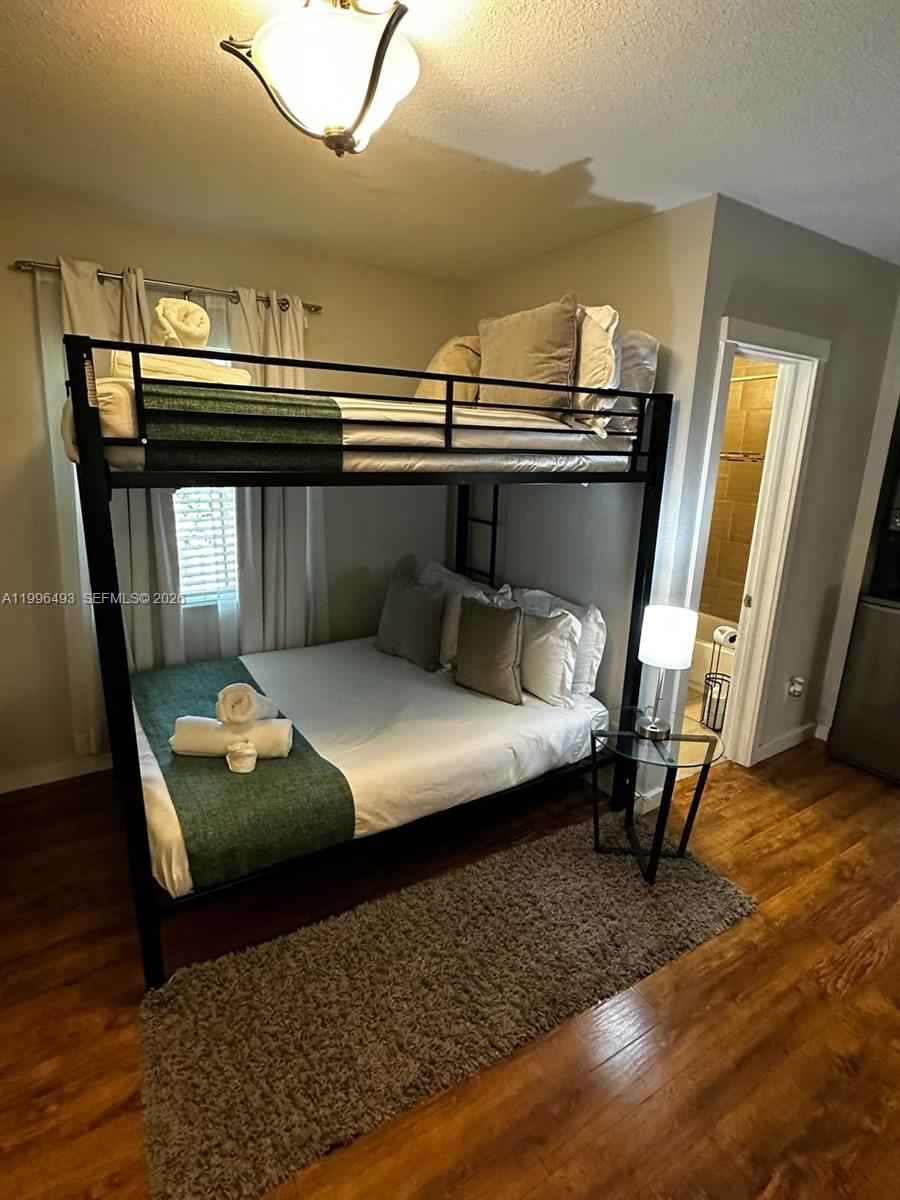 A bedroom features a black metal bunk bed with a lower full-size mattress and wood flooring — 1448 Dewey St # 1448, Hollywood FL 33020, HOLLYWOOD, FL