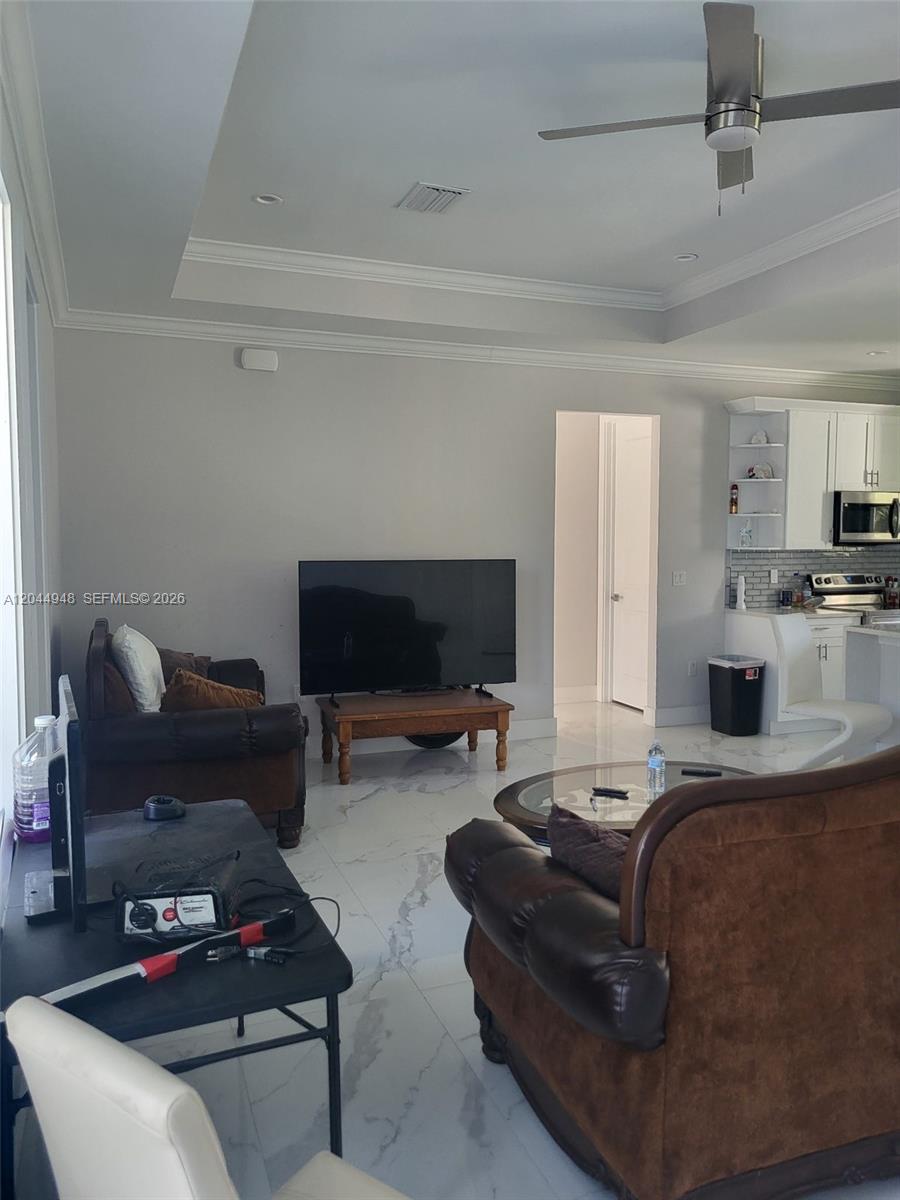 A living room features white marble-style tile floors, brown leather furniture, and a ceiling fan — 4276 12th Avenue, Naples FL 34120, NAPLES, FL