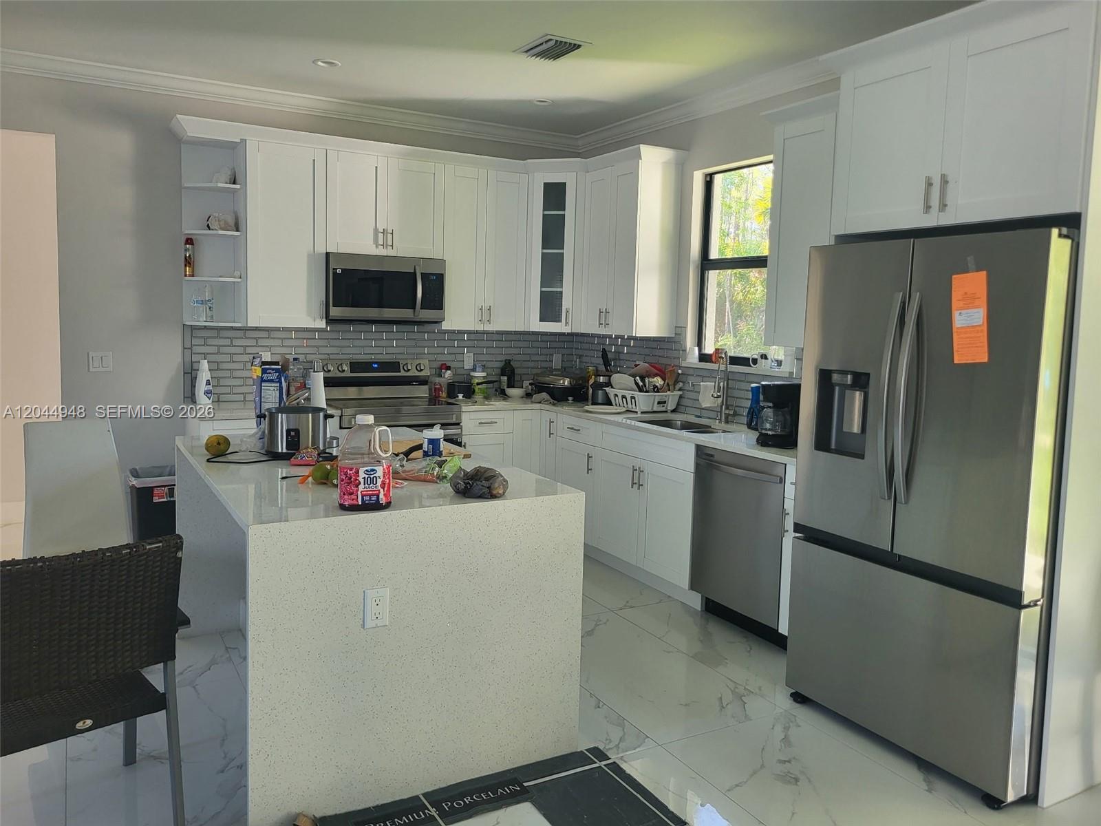 A kitchen features white cabinets, stainless steel appliances, a quartz island, and marble-look tile flooring — 4276 12th Avenue, Naples FL 34120, NAPLES, FL