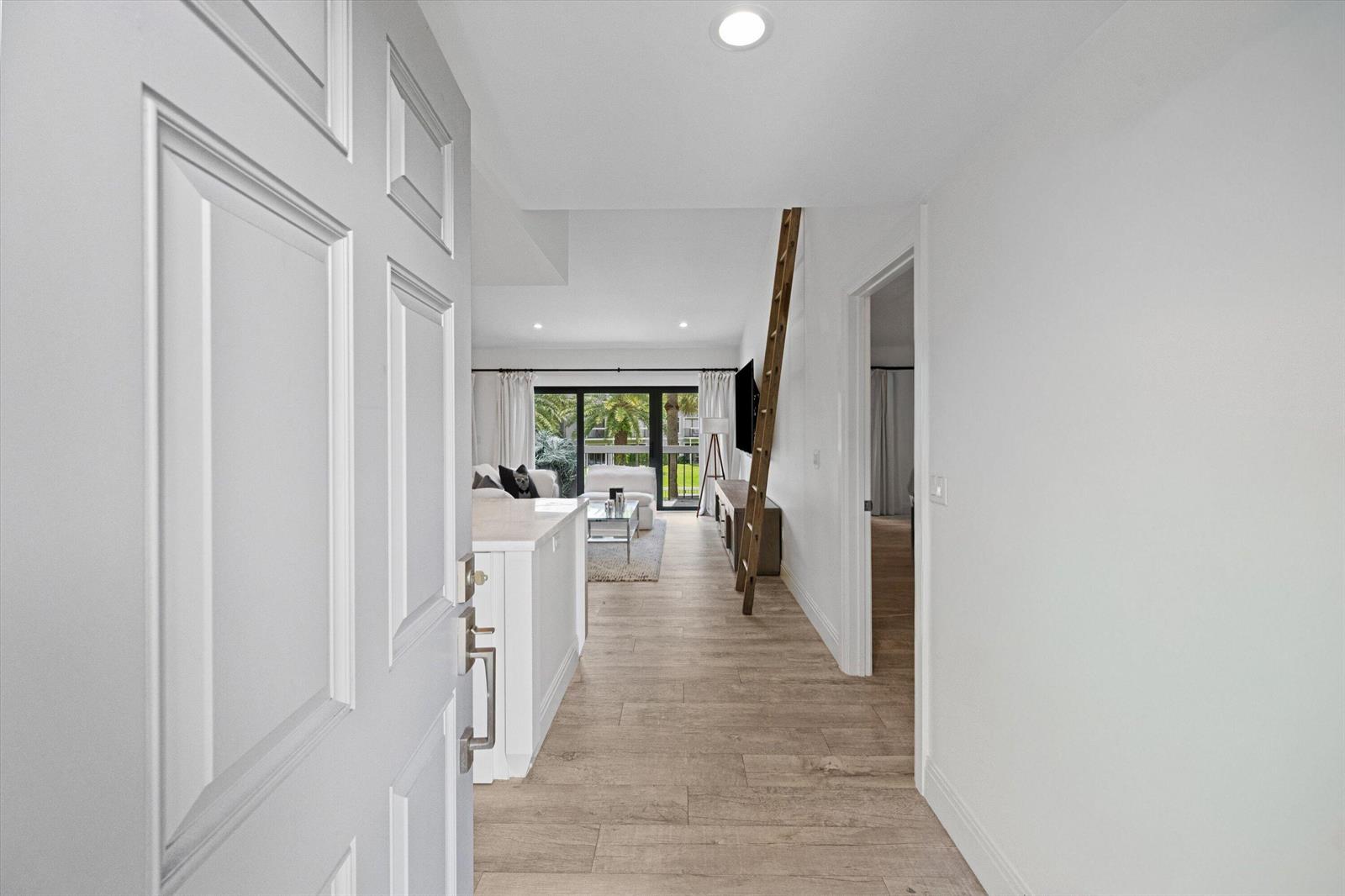 A view from an open doorway into a bright living area with wood-look flooring — 11863 Wimbledon Circle # 532, Wellington FL 33414, WELLINGTON, FL