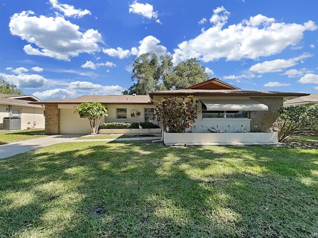 A single-story house with a stone facade, a garage, and a large front lawn — 2819 THISTLE COURT S, PALM HARBOR, FL