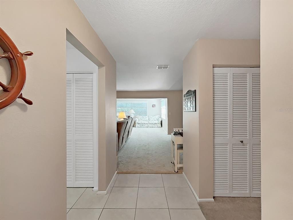 A tiled entryway leads into a carpeted living room with white louvered closet doors — 2819 THISTLE COURT S, PALM HARBOR, FL