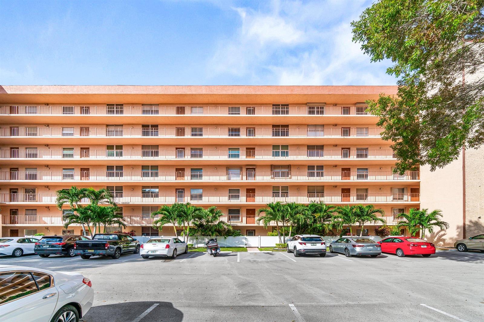 A multi-story apartment building with balconies and a parking lot in the foreground — 14623 Bonaire Boulevard # 608, Delray Beach FL 33446, DELRAY BEACH, FL
