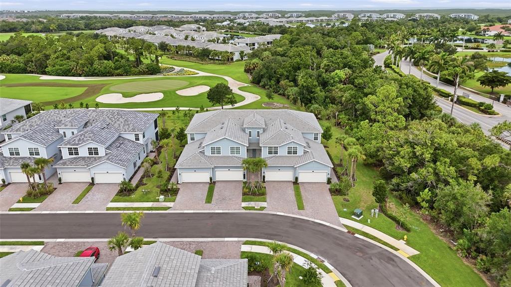 An aerial view shows a multi-unit residential building with gray roofs and paved driveways — 14827 BIRCHWOOD COURT UNIT 6122, PUNTA GORDA, FL