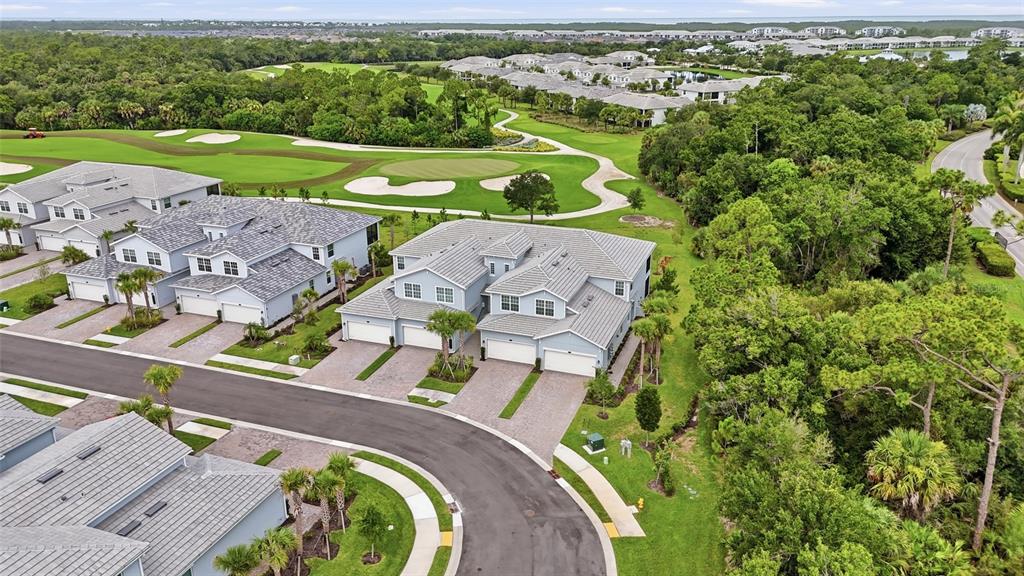 An aerial view shows multi-family residential buildings situated next to a golf course and trees — 14827 BIRCHWOOD COURT UNIT 6122, PUNTA GORDA, FL