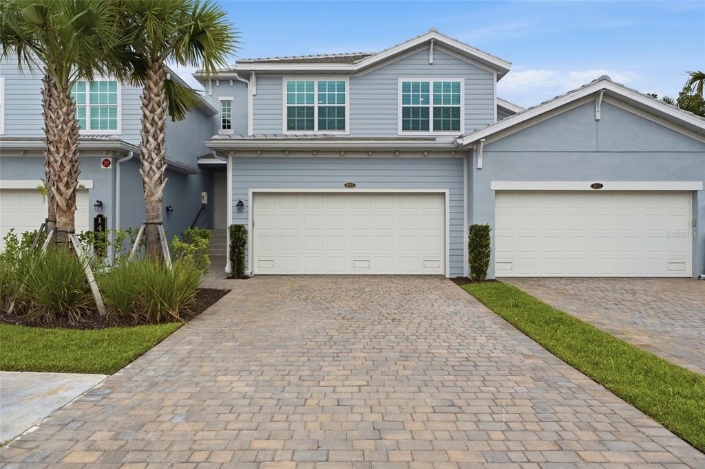 A two-story light blue house with a paved driveway and two white garage doors — 14827 BIRCHWOOD COURT UNIT 6122, PUNTA GORDA, FL