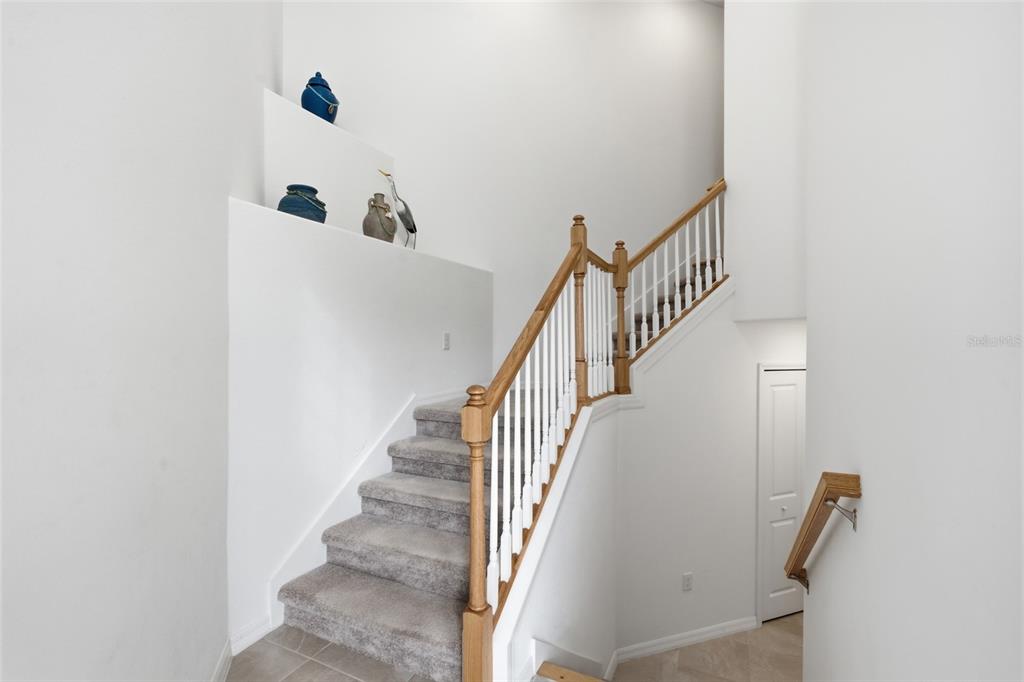 A staircase with carpeted steps, wooden railings, and white balusters leads to an upper level — 14827 BIRCHWOOD COURT UNIT 6122, PUNTA GORDA, FL