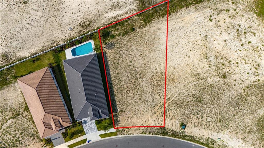 An aerial view shows a vacant residential lot next to a house with a pool — 74 DEL PALMA DRIVE, PALM COAST, FL