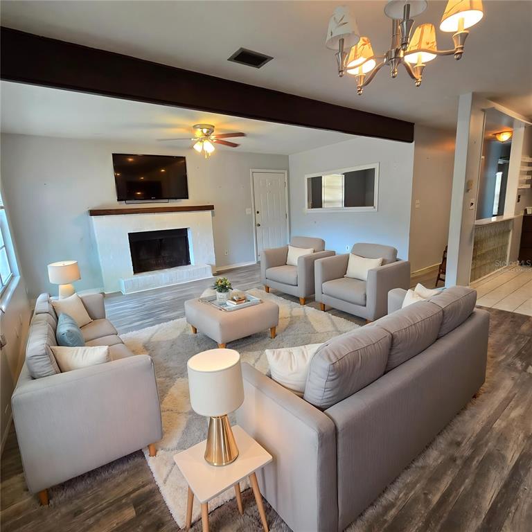 A bedroom features a tufted gray bed, a ceiling fan, and a window with blinds — 701 NW 24TH AVENUE, GAINESVILLE, FL