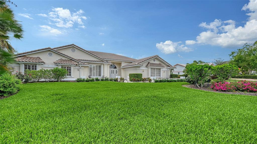 A single-story beige house with a tiled roof sits behind a large green lawn — 3988 LOSILLIAS DRIVE, SARASOTA, FL