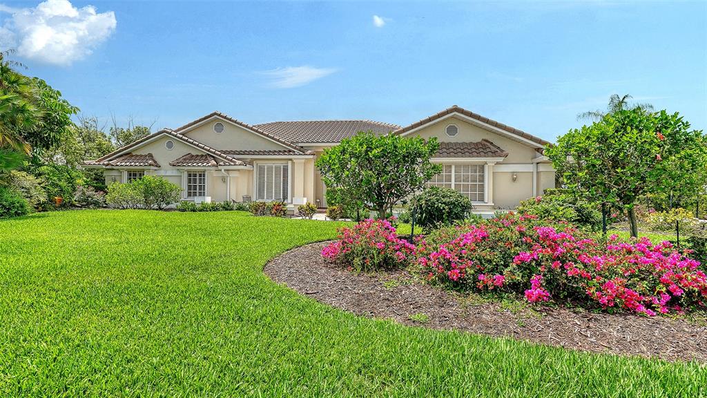 A single-story house with a beige exterior, tile roof, and a landscaped front yard — 3988 LOSILLIAS DRIVE, SARASOTA, FL