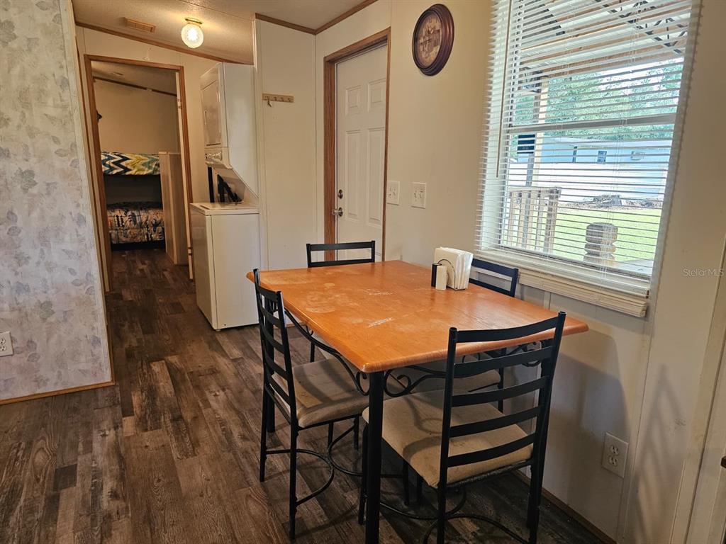 A dining area features a wooden table with black chairs, wood-look flooring, and a window — 9050 SE 196TH TERRACE, OCKLAWAHA, FL