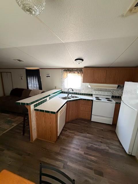 A kitchen with wood cabinets, white appliances, and a breakfast bar overlooks a living area — 9050 SE 196TH TERRACE, OCKLAWAHA, FL